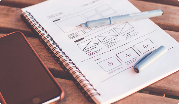 Um caderno com desenhos de containers e estruturas de um site, representando o briefing do projeto.